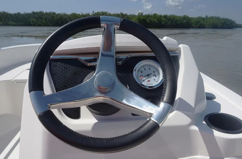 Slide: The Image of Steering wheel of 2023 Boston Whaler 130 Super Sport boat on water. - 13