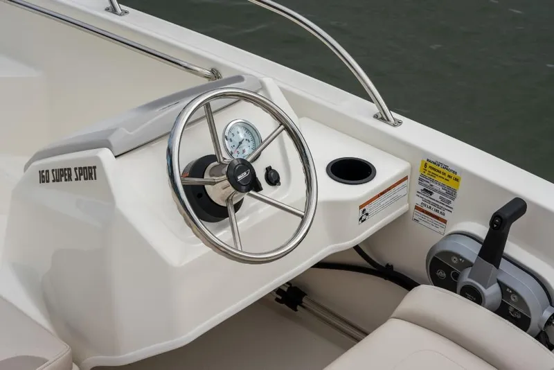 Slide: The Image of 2023 Boston Whaler 160 Super Sport boat dashboard with steering wheel and controls. - 12