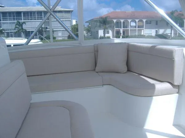Slide: The Image of 2024 Jersey Cape 48 Custom boat interior seating area with beige cushions. - 11