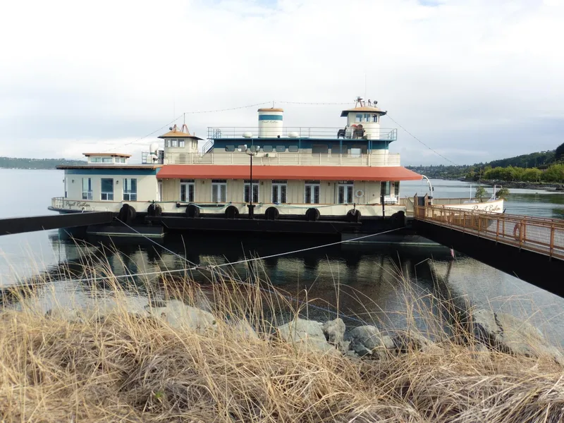 Slide: The Image of 1936 Custom Ferry docked by the shore with a red roof and white exterior. - 13
