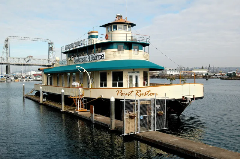 Slide: The Image of 1936 Custom Ferry Point Ruston docked at a marina with a bridge in the background. - 2