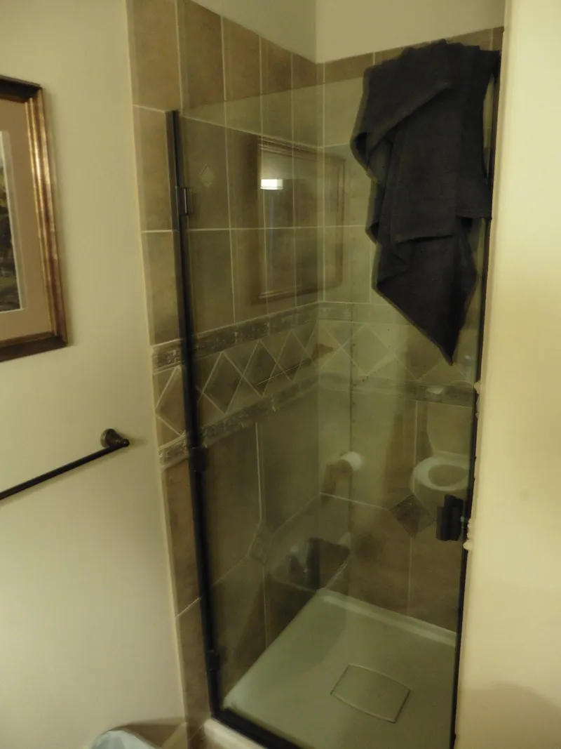 Slide: The Image of Small bathroom with glass shower enclosure and towel hanging on door. - 44