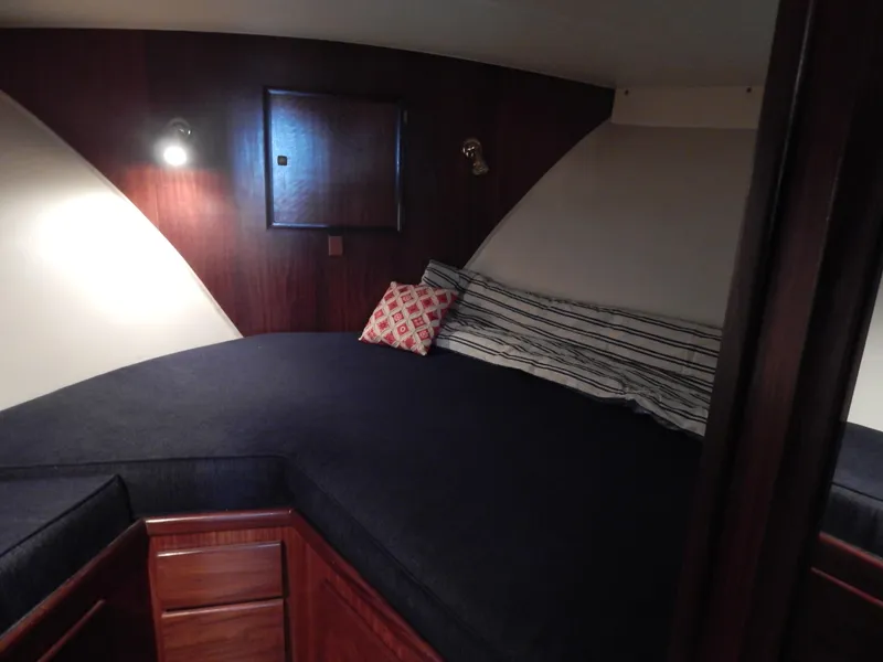 Slide: The Image of 1972 Hatteras 38 Convertible cabin with cozy bed, wooden interior, and ambient lighting. - 16