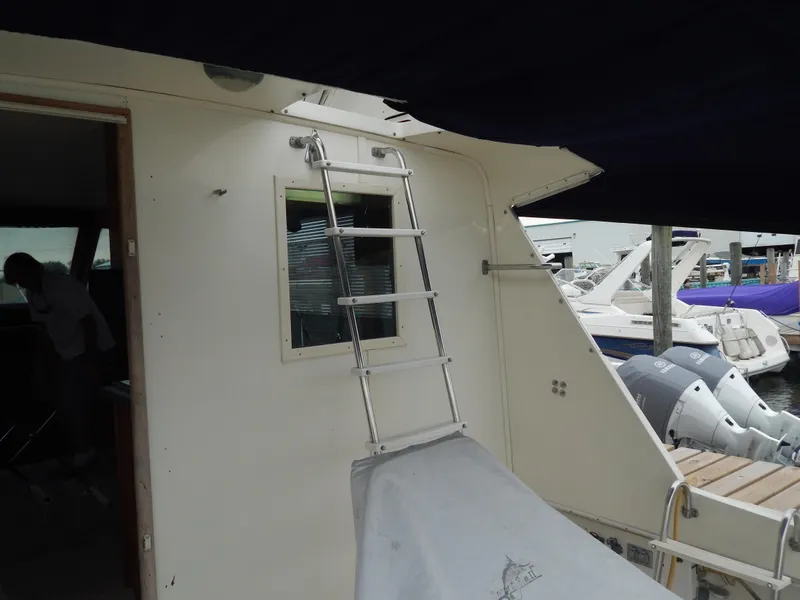 Slide: The Image of 1972 Hatteras 38 Convertible yacht with ladder and docked boats in background. - 8