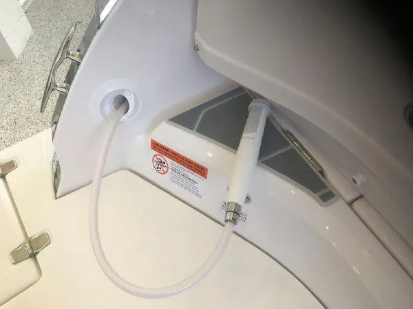 Slide: The Image of 2022 Regal 29 OBX boat shower hose and nozzle in white compartment. - 12