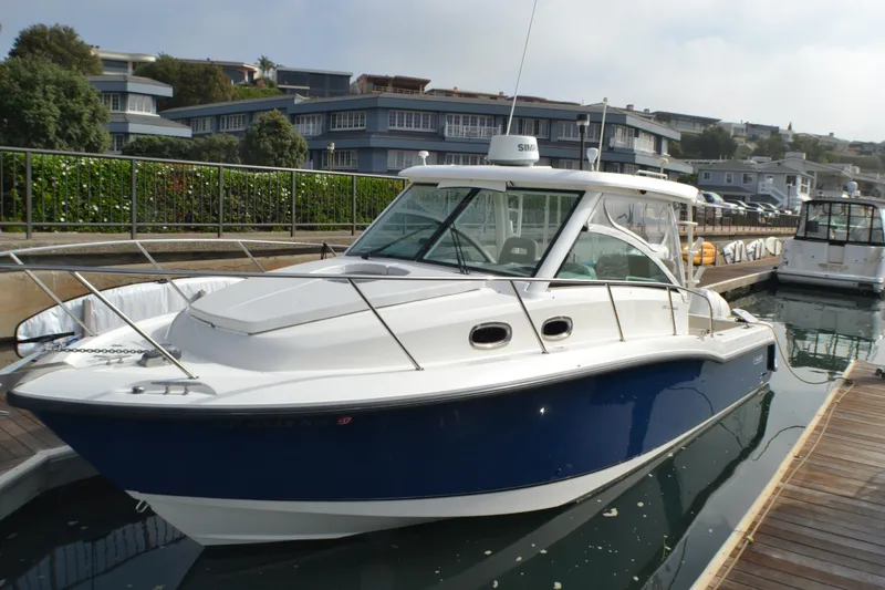 The Image of 2016 Boston Whaler 315 Conquest boat on stands, blue and white exterior, clear sky background. - 0