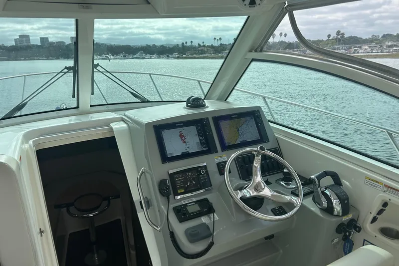 Slide: The Image of 2016 Boston Whaler 315 Conquest interior with seating and helm, docked by the water. - 18