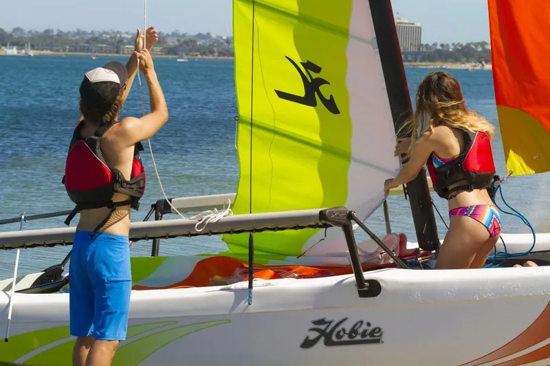 Slide: The Image of Two people preparing a 2023 Hobie Cat Getaway sailboat on a sunny beach. - 4