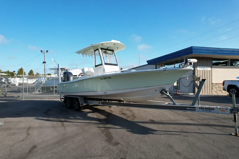 Slide: The Image of 2019 Sea Hunt BX 25 FS boat on trailer at a marina under clear blue sky. - 2