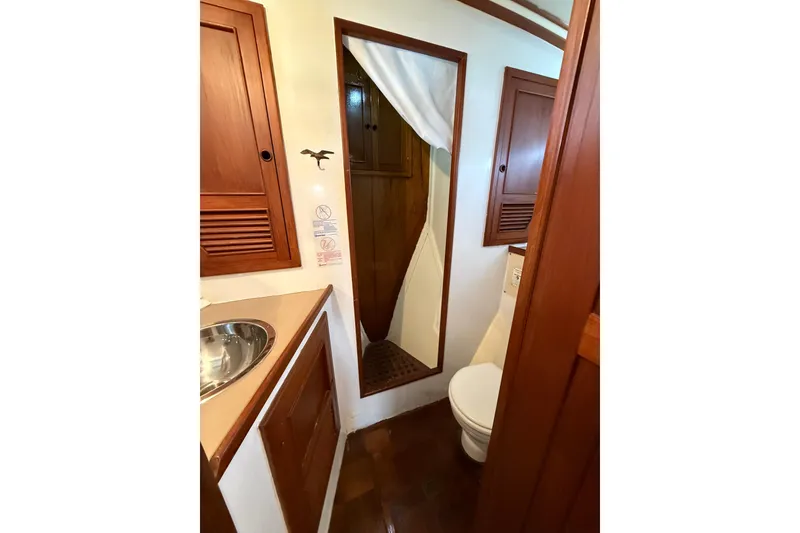 Slide: The Image of 1982 Krogen 42 yacht bathroom with wooden cabinets, mirror, and stainless steel sink. - 11