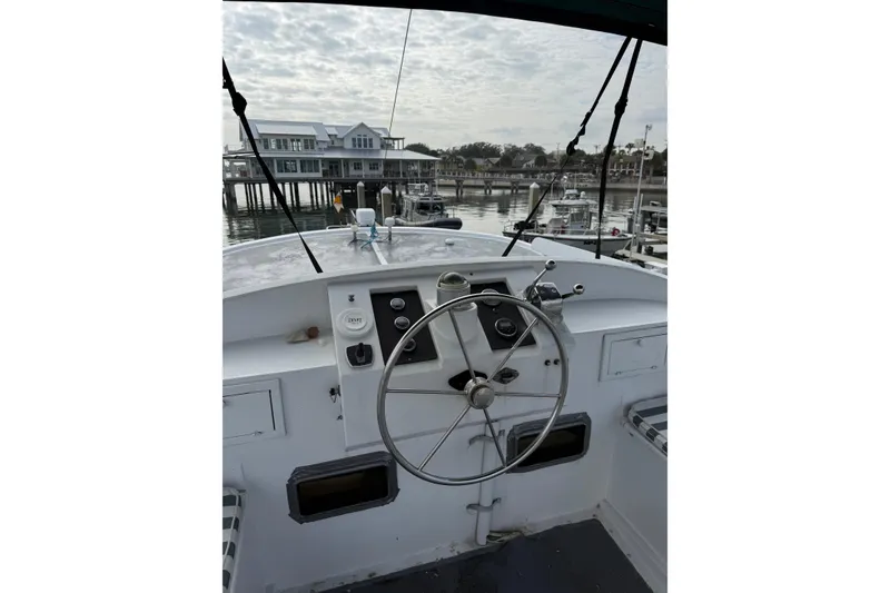 Slide: The Image of 1982 Krogen 42 boat helm with steering wheel, docked at marina under cloudy sky. - 24