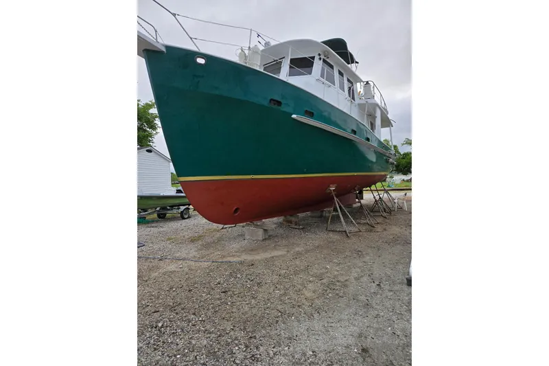Slide: The Image of 1982 Krogen 42 boat on dry dock, green hull, red bottom, overcast sky. - 3