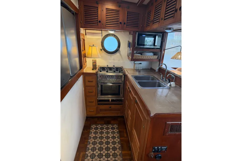 Slide: The Image of 1982 Krogen 42 yacht kitchen with stove, sink, microwave, and porthole window. - 8