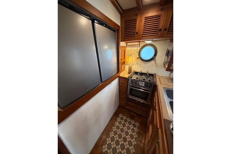 Slide: The Image of Cozy 1982 Krogen 42 galley with stove, fridge, and porthole window. - 9