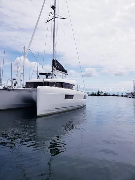The Image of 2019 Lagoon 40 catamaran docked on calm water under a cloudy sky. - 0