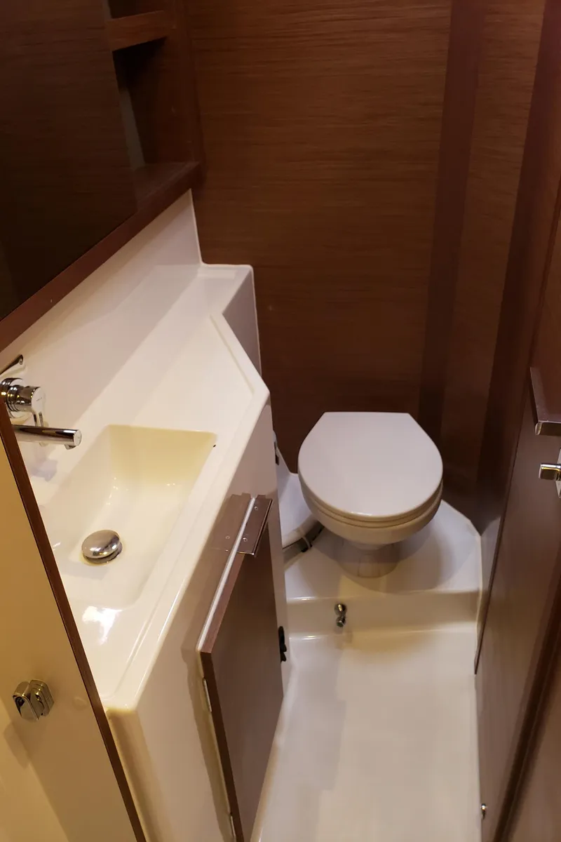 Slide: The Image of 2019 Lagoon 40 yacht bathroom with sink and toilet, featuring modern wood accents. - 17
