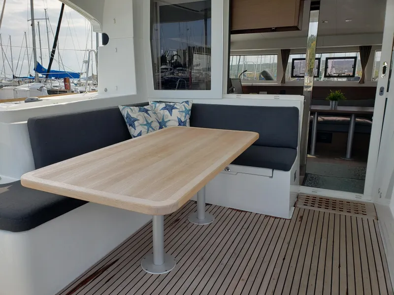 Slide: The Image of Outdoor seating area on 2019 Lagoon 40 catamaran with wooden table and cushioned benches. - 4