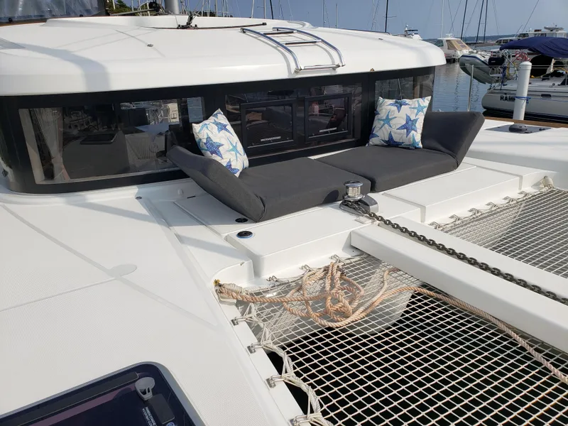 Slide: The Image of 2019 Lagoon 40 catamaran with cushioned seating and nautical decor in a marina setting. - 9