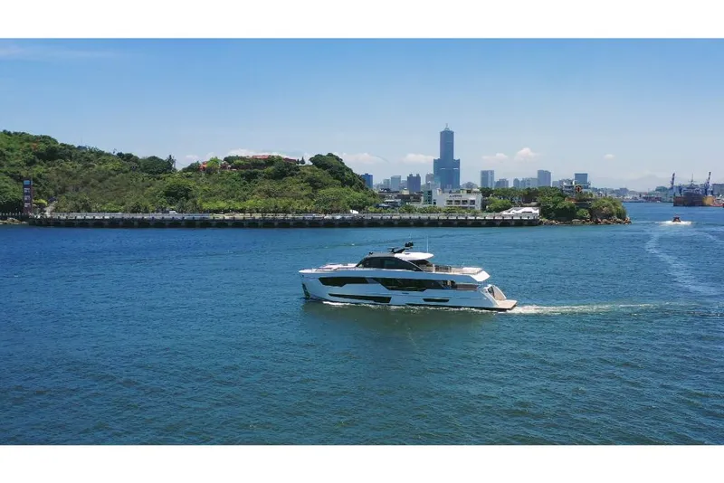 Slide: The Image of Ocean Alexander 30R 2023 yacht cruising near a coastal city skyline. - 2