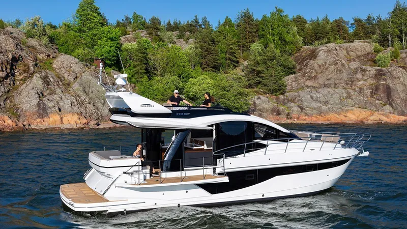 Slide: The Image of 2023 Galeon 470 Sky yacht cruising near rocky shoreline with lush greenery. - 8