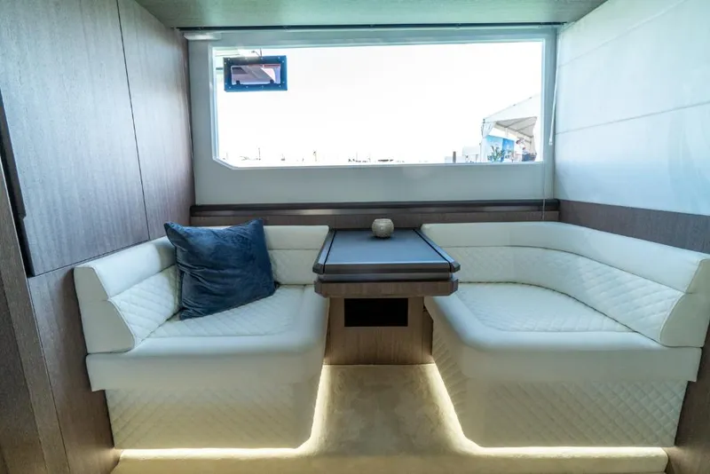 Slide: The Image of Interior seating area of 2023 Galeon 650 Sky yacht with white upholstery and wooden table. - 15