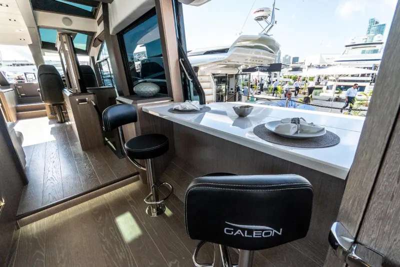 Slide: The Image of Interior of 2023 Galeon 650 Sky yacht with modern dining area and bar stools. - 6