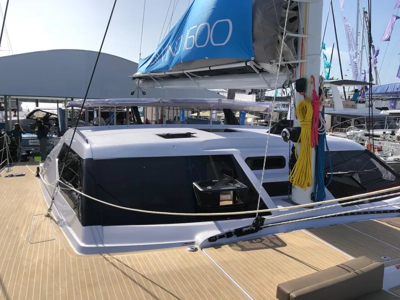Slide: The Image of 2025 Seawind 1600 catamaran with blue sail, docked at marina. - 12