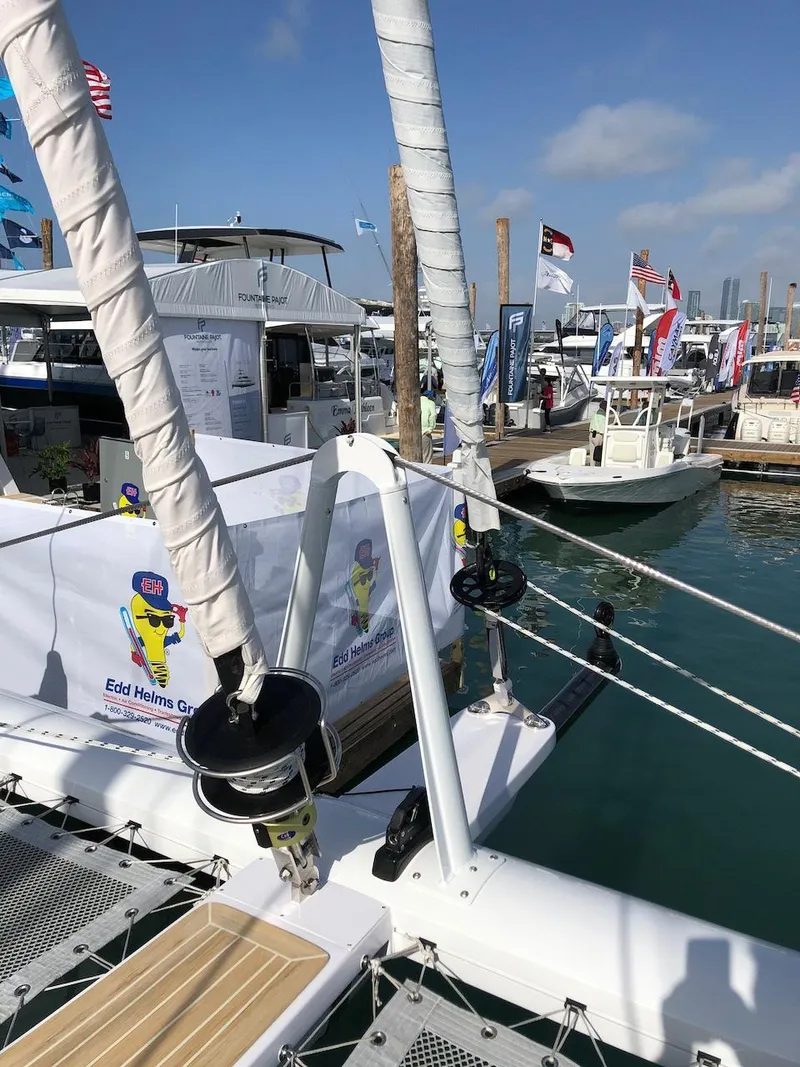 Slide: The Image of 2025 Seawind 1600 catamaran at a marina with flags and boats in the background. - 17