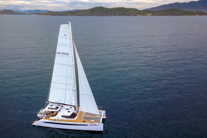 Slide: The Image of 2025 Seawind 1600 catamaran sailing on open water with scenic mountain backdrop. - 24