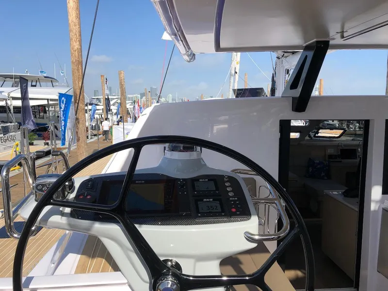 Slide: The Image of 2025 Seawind 1600 yacht cockpit with steering wheel and navigation instruments at a marina. - 7