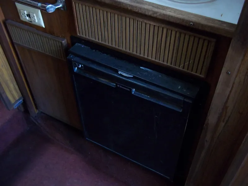 Slide: The Image of 1984 Sea Ray SRV 260 Sundancer interior, showing built-in refrigerator and wooden cabinetry. - 19