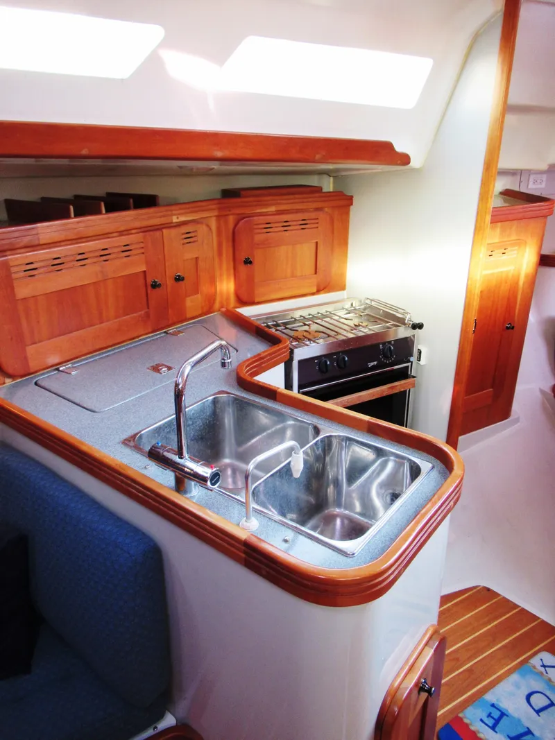 Slide: The Image of 2004 C&C 110 yacht interior with wooden cabinets and compact kitchen area. - 18