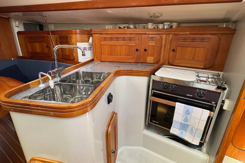 Slide: The Image of Compact yacht kitchen with wooden cabinets, dual sink, and stove in a 2004 C&C 110 model. - 21