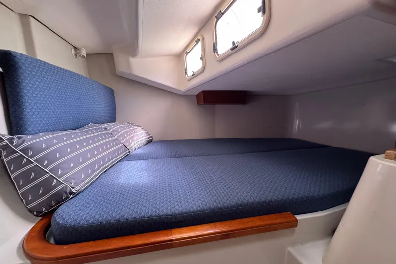 Slide: The Image of Cozy cabin interior of 2004 C&C 110 sailboat with blue cushions and nautical-themed pillows. - 23