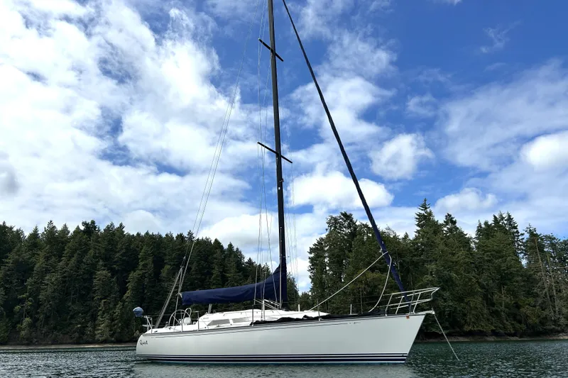 Slide: The Image of Sailboat C&C 110 (2004) on calm water with forested shoreline and cloudy sky. - 40