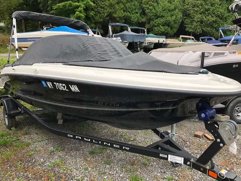 Slide: The Image of 2018 Bayliner 160 Bowrider boat on trailer, covered, parked outdoors. - 1