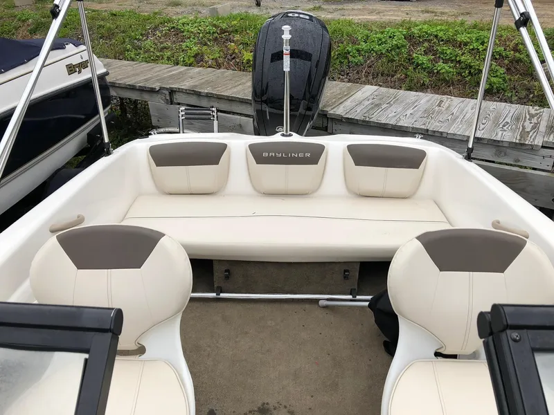 Slide: The Image of 2018 Bayliner 160 Bowrider interior with beige seating and outboard motor. - 3