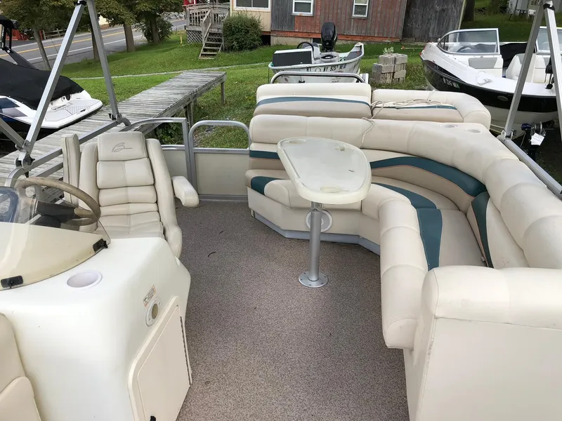 Slide: The Image of 2001 Bennington 2250 RL pontoon boat with spacious seating and table, docked near other boats. - 4