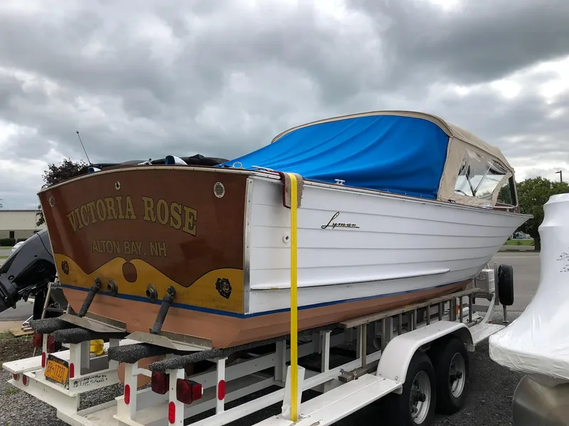 Slide: The Image of 1962 Lyman 245 boat "Victoria Rose" on trailer, covered with blue tarp, cloudy sky. - 2