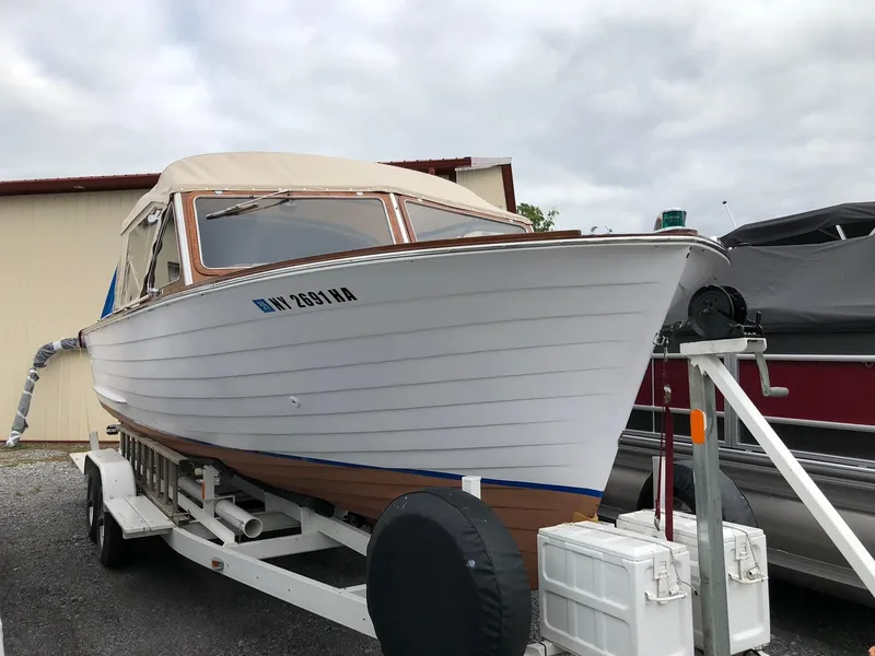 Slide: The Image of 1962 Lyman 245 boat on trailer, white hull, parked outdoors under cloudy sky. - 5