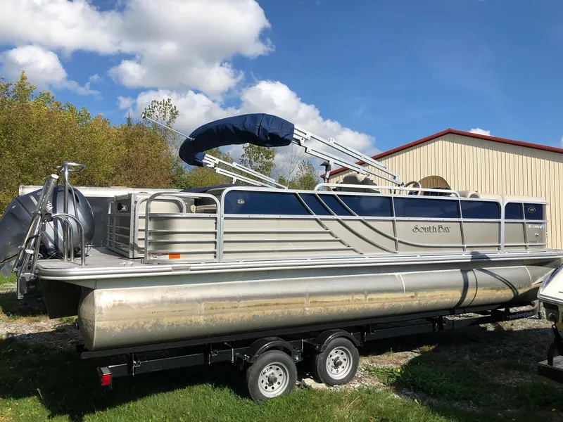 Slide: The Image of 2015 South Bay 522 FCR pontoon boat on trailer, parked outdoors under blue sky. - 1