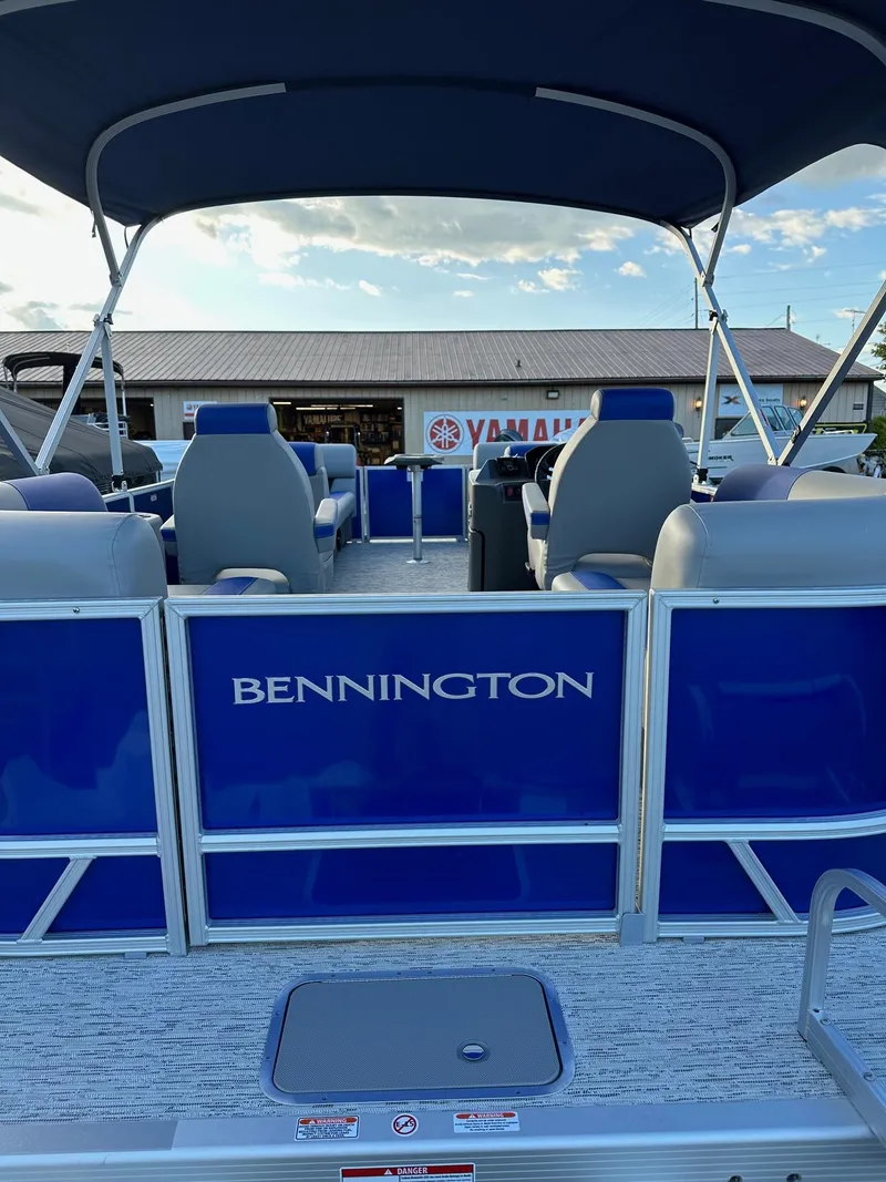 Slide: The Image of 2025 Bennington 21 SSR Quad Bench pontoon boat with blue seating and canopy. - 13