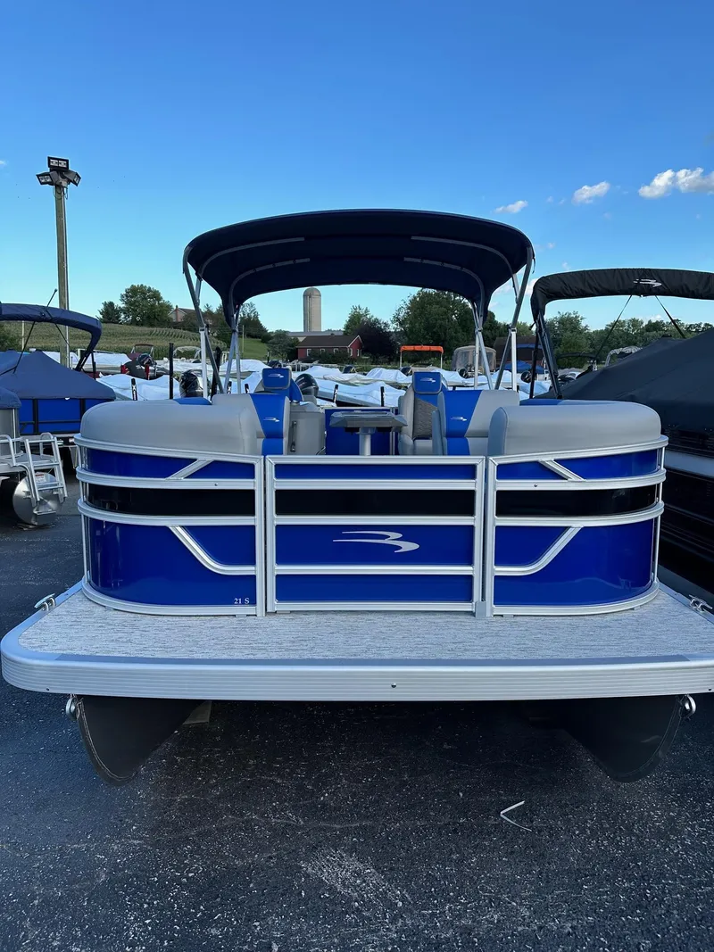 Slide: The Image of 2025 Bennington 21 SSR Quad Bench pontoon boat, blue exterior, parked outdoors. - 5