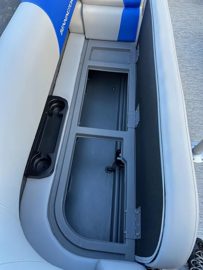 Slide: The Image of 2025 Bennington 21 SSR Quad Bench storage compartment with cup holders and blue accents. - 6