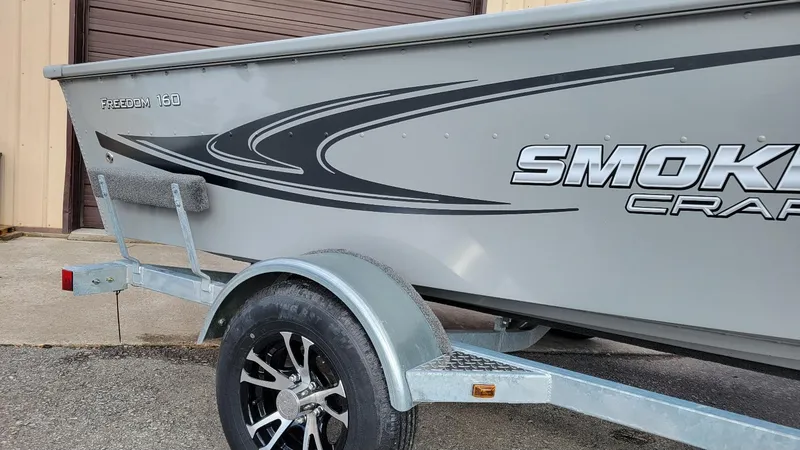 Slide: The Image of 2023 Smoker Craft Freedom 16 boat on trailer, featuring sleek design and graphics. - 3