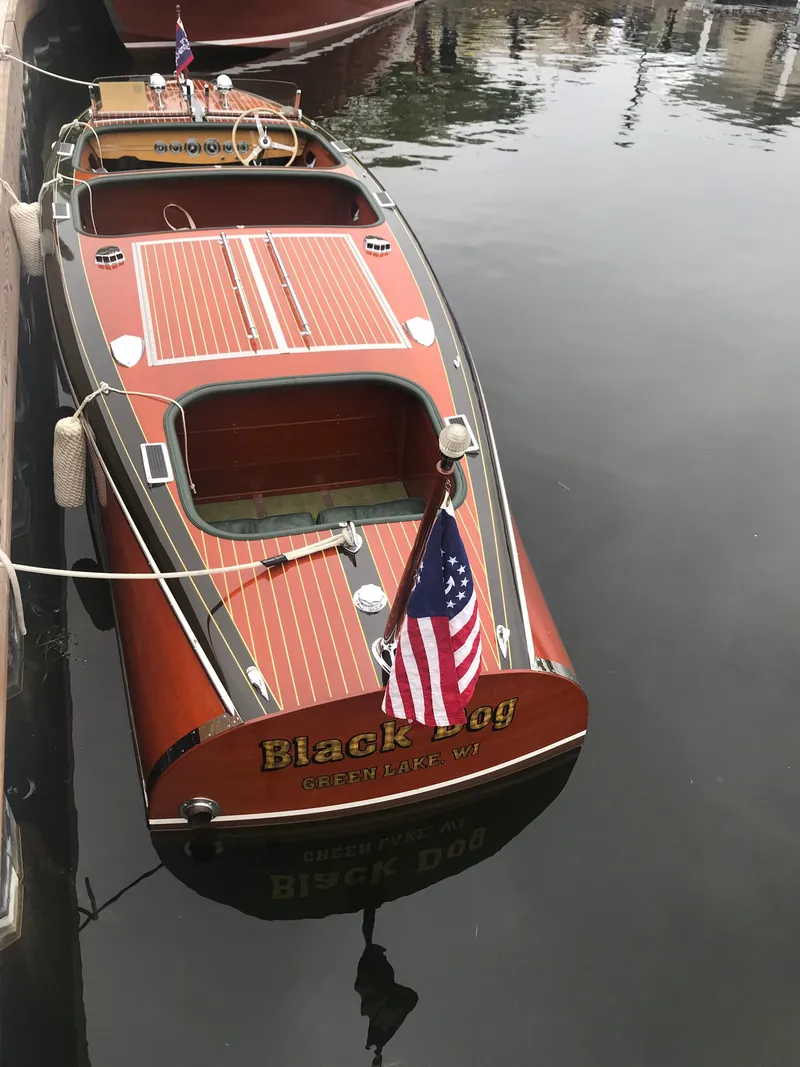 Slide: The Image of 1940 Chris-Craft Deluxe Runabout boat docked, featuring wooden deck and American flag. - 2