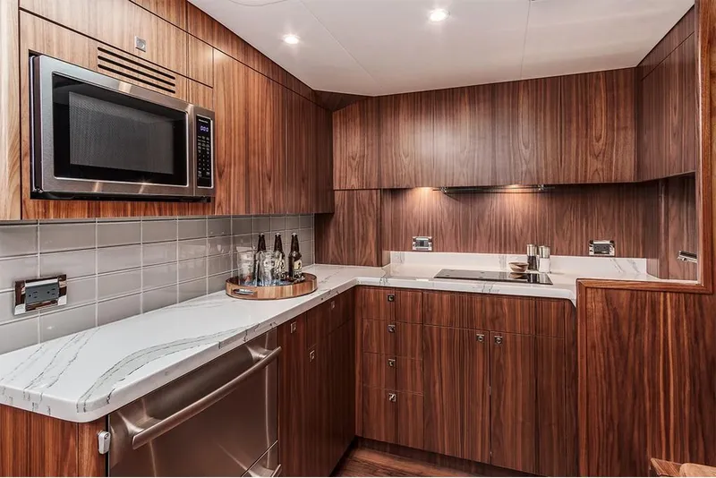 Slide: The Image of Modern kitchen in 2022 Hatteras GT45X Open yacht with wood cabinetry and stainless steel appliances. - 10