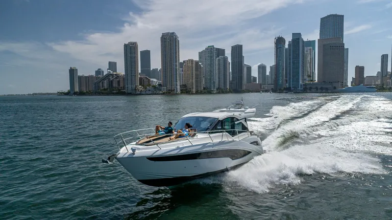 Slide: The Image of 2023 Galeon 425 HTS cruising near a city skyline on a sunny day. - 1