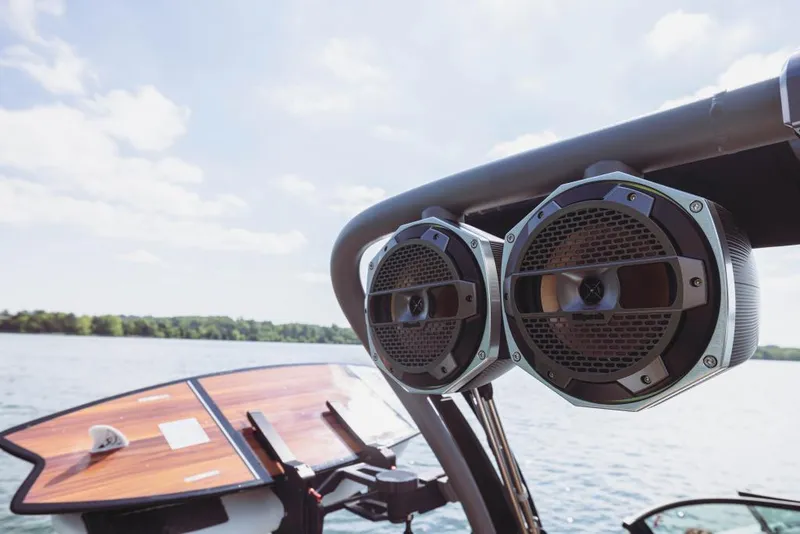 Slide: The Image of 2023 MasterCraft X22 boat with mounted speakers on a sunny lake. - 12