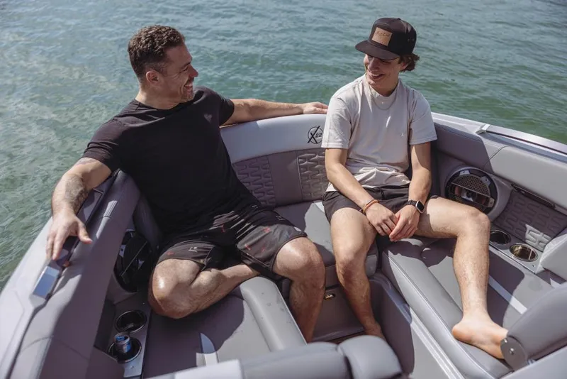 Slide: The Image of Two men relaxing on a 2023 MasterCraft X22 boat. - 13